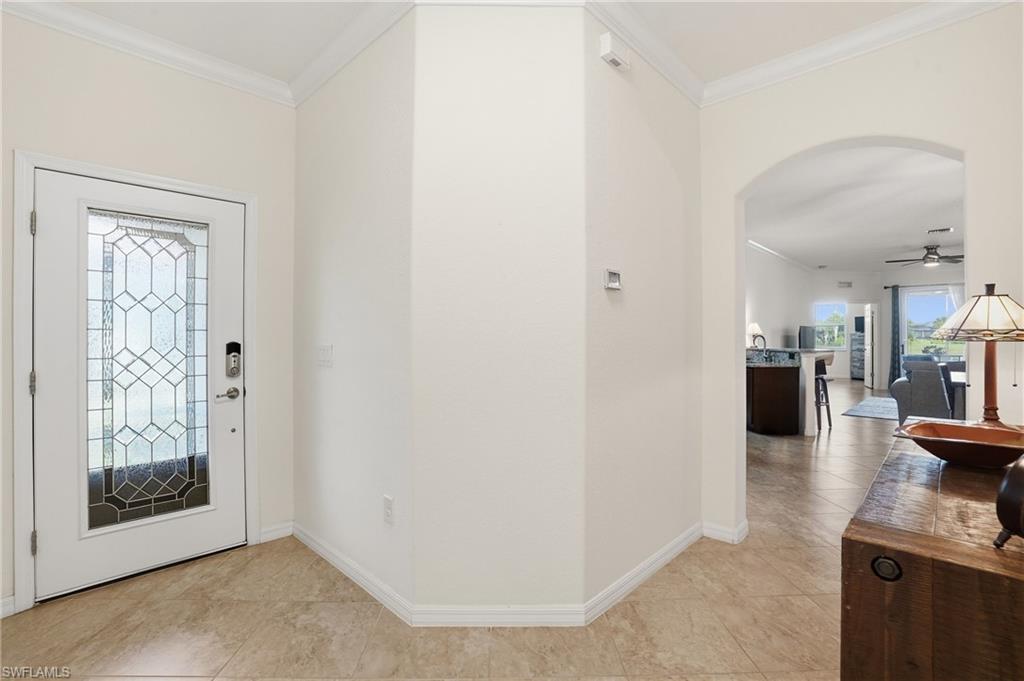 Entrance foyer featuring ornamental molding, a ceiling fan, and arched walkways