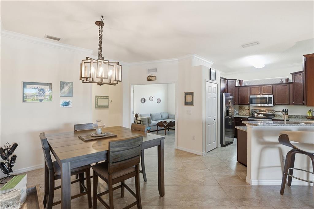 Dining space with crown molding, a chandelier, and light tile patterned floors