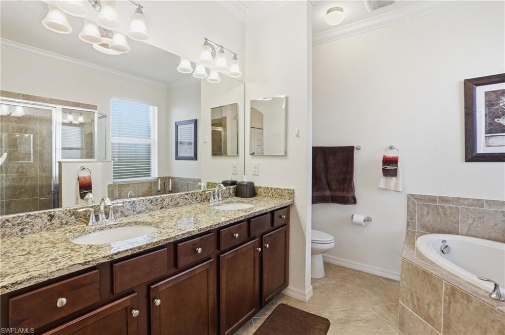 Full bath with ornamental molding, a bath, double vanity, a shower stall, and light tile patterned floors