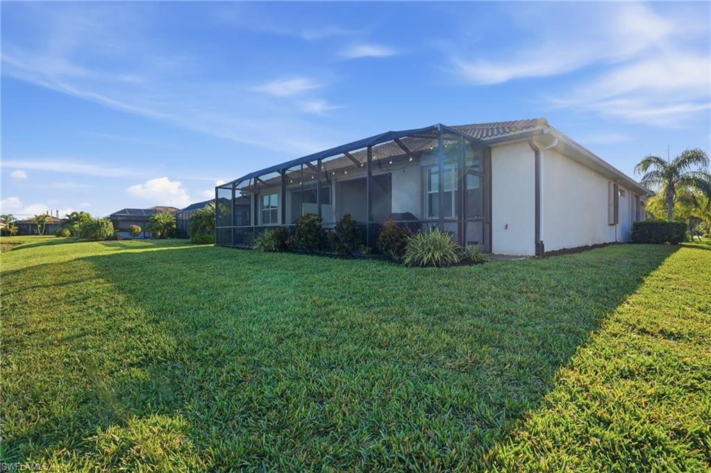View of side of home with a sunroom, a lawn, a lanai, and stucco siding