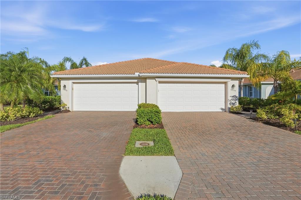View of front of house featuring stucco siding, a tiled roof, and a garage
