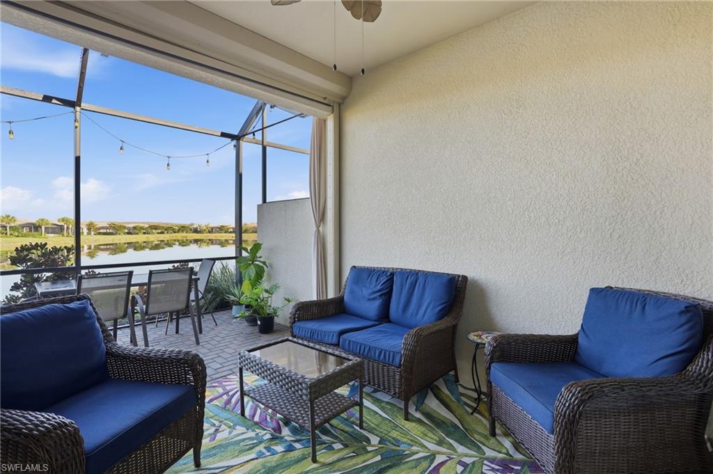 View of patio with a sunroom, ceiling fan, a water view, an outdoor living space, and a lanai