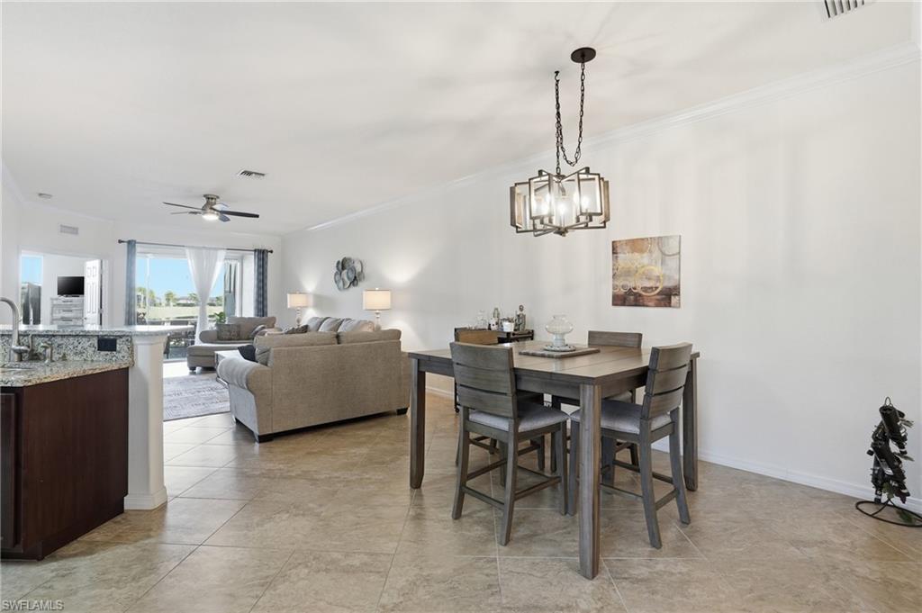Dining area featuring ornamental molding, a ceiling fan, and a chandelier