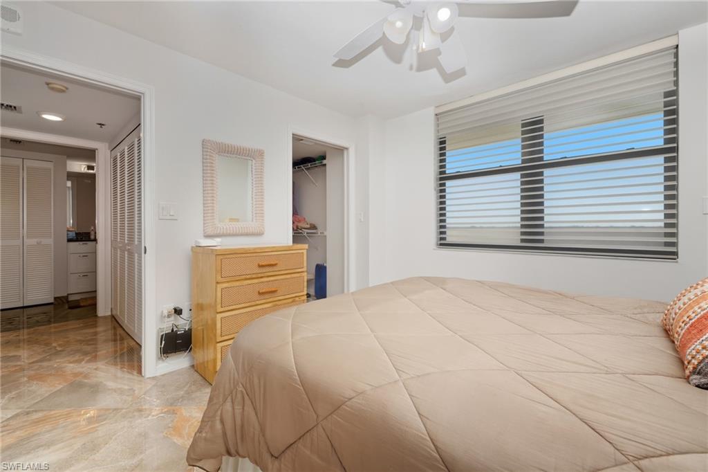 Bedroom with a ceiling fan, a spacious closet, and light marble finish floors