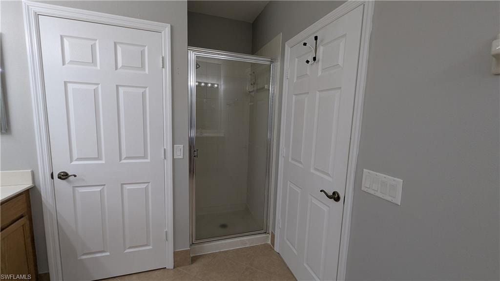 Full bath featuring light tile patterned floors, vanity, and a stall shower