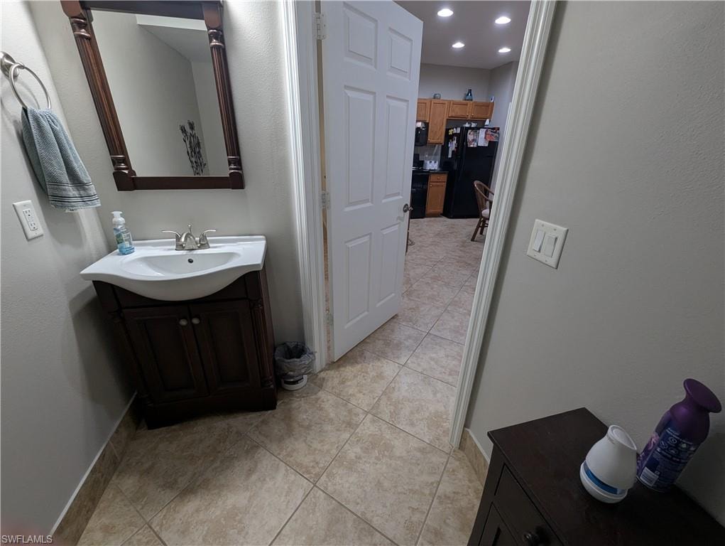 Bathroom featuring vanity, light tile patterned flooring, a textured wall, and recessed lighting