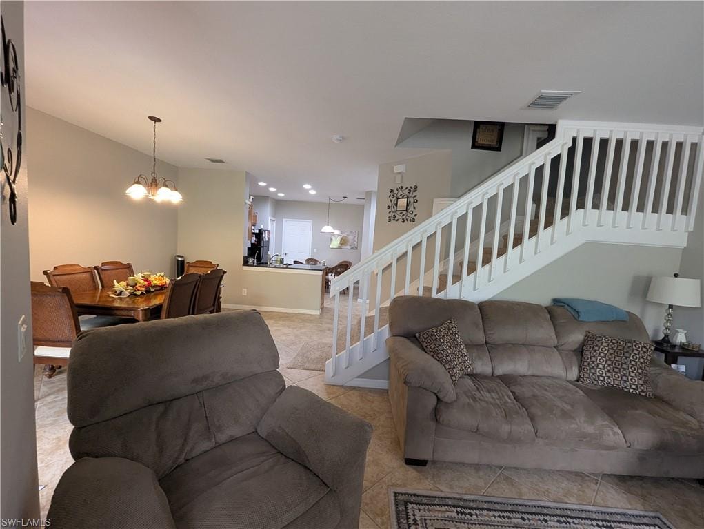 Living area with stairs, a chandelier, light tile patterned flooring, and recessed lighting