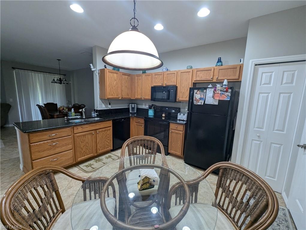 Kitchen featuring black appliances, pendant lighting, brown cabinets, and recessed lighting