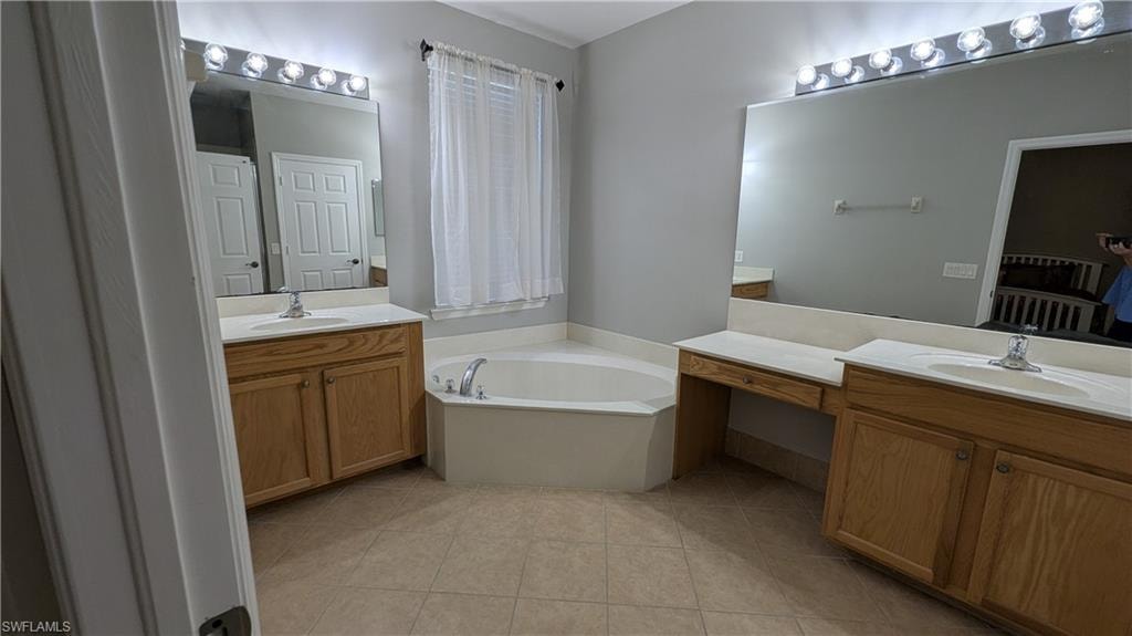 Bathroom with two vanities, a bath, and light tile patterned floors