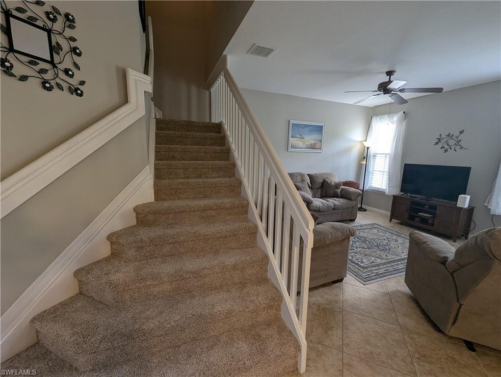 Staircase with tile patterned flooring and ceiling fan