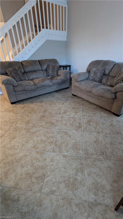 Living area featuring stairs and light tile patterned floors