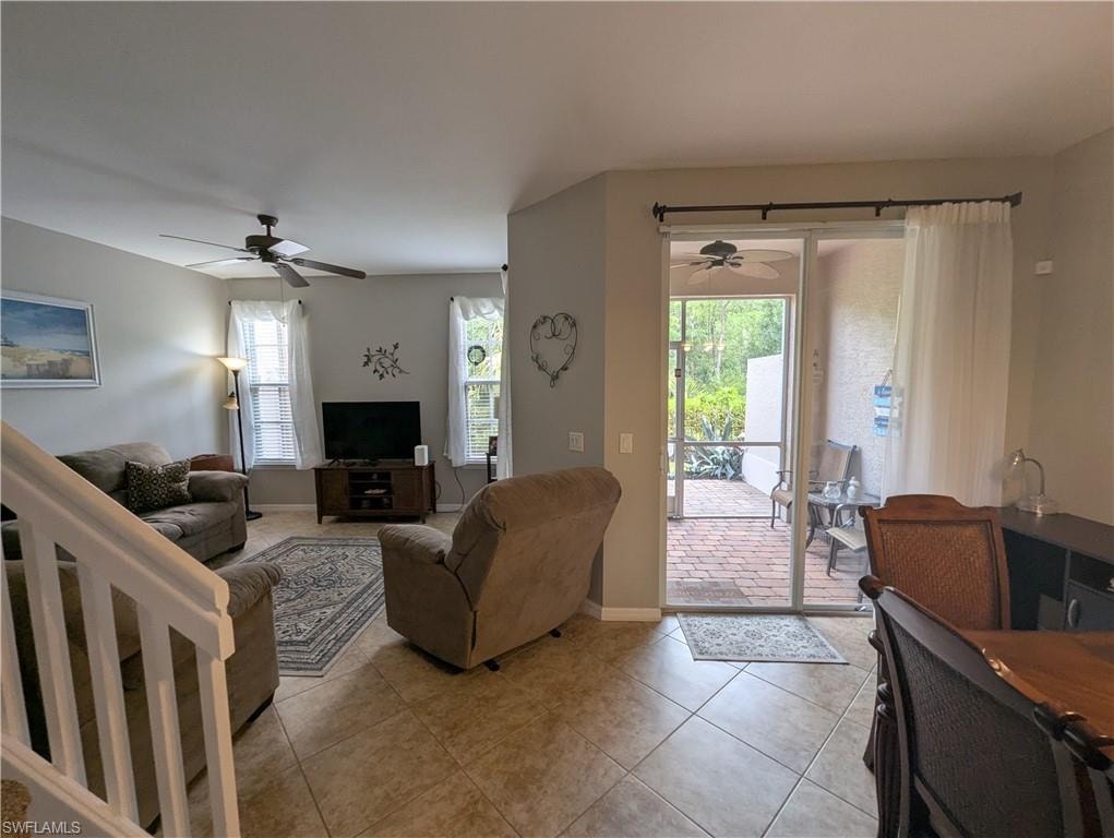 Tiled living room featuring a ceiling fan and baseboards