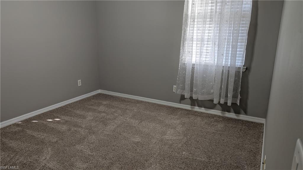 Carpeted spare room with baseboards