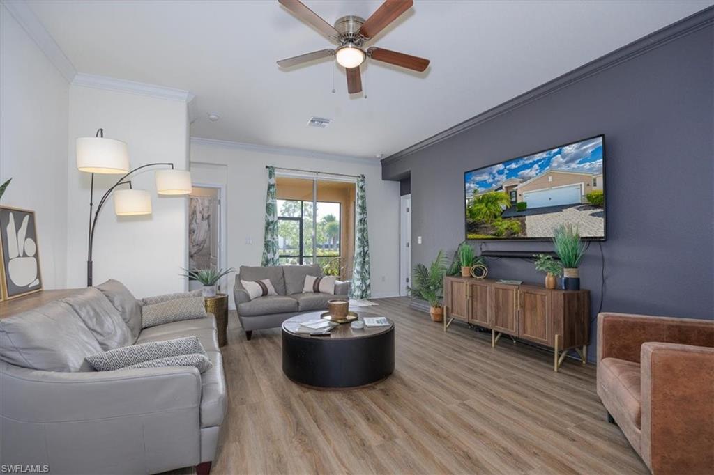 Living room with easy care  flooring, ornamental molding, and ceiling fan