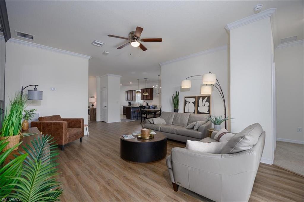 Living room with ornamental molding, easy care floors, and ceiling fan