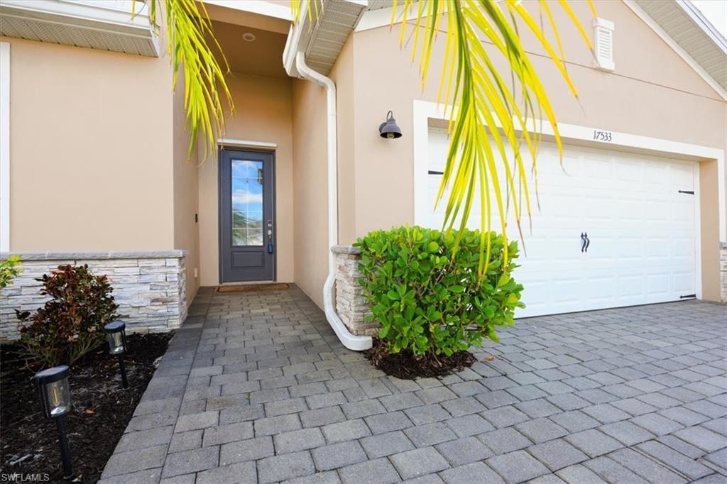 Entrance to property with a garage, stucco siding, and decorative driveway