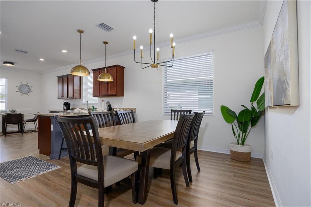 Dining space featuring easy care floors, ornamental molding, a chandelier, and healthy amount of natural light