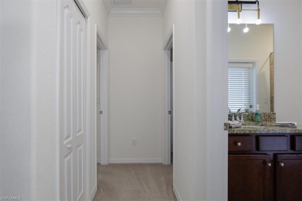 Hall with light colored carpet and crown molding