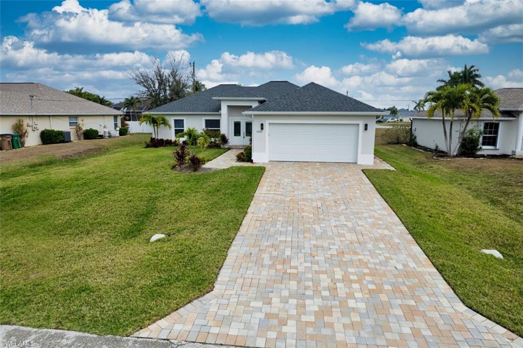 Single story home with decorative driveway, a front yard, a garage, and stucco siding