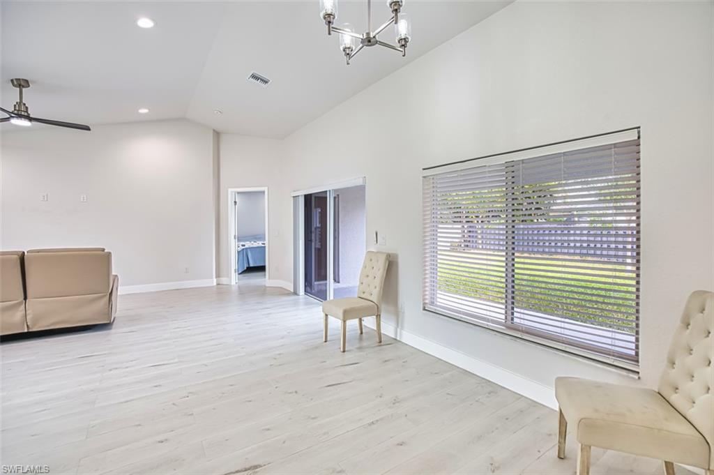 Unfurnished room featuring a chandelier, light wood-style floors, high vaulted ceiling, recessed lighting, and ceiling fan