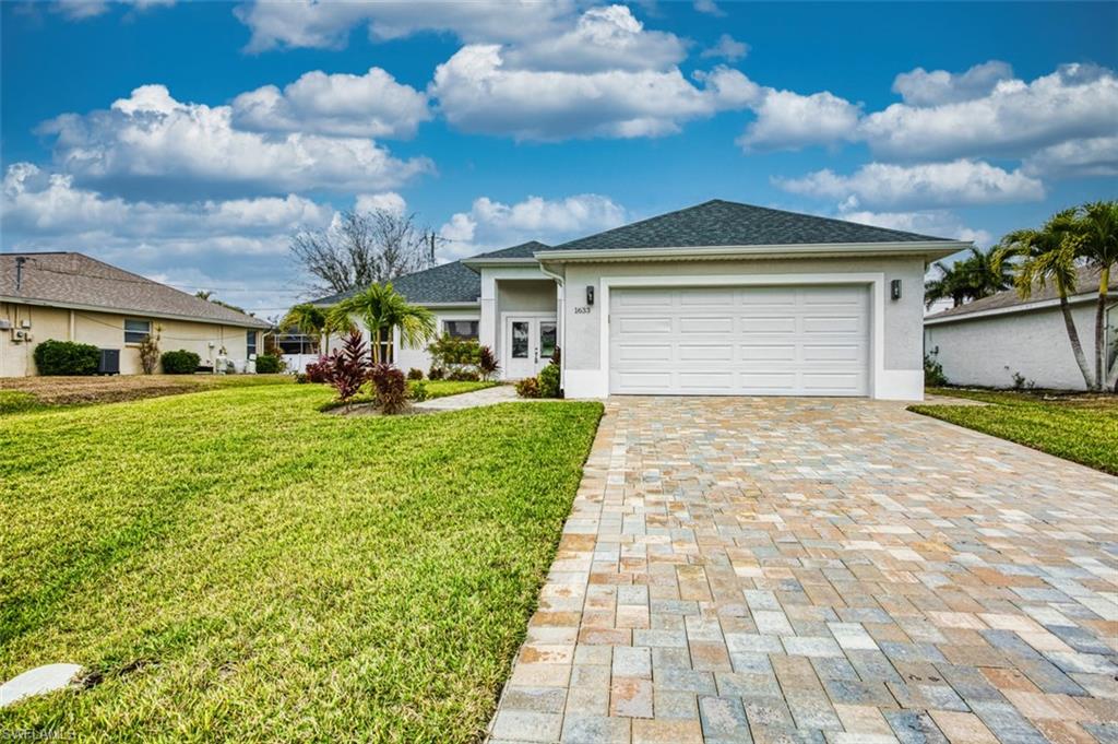 Ranch-style house with stucco siding, a front lawn, decorative driveway, a garage, and a shingled roof