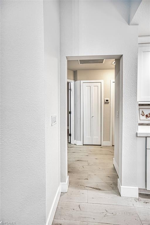Hall featuring a textured wall and light wood-style flooring
