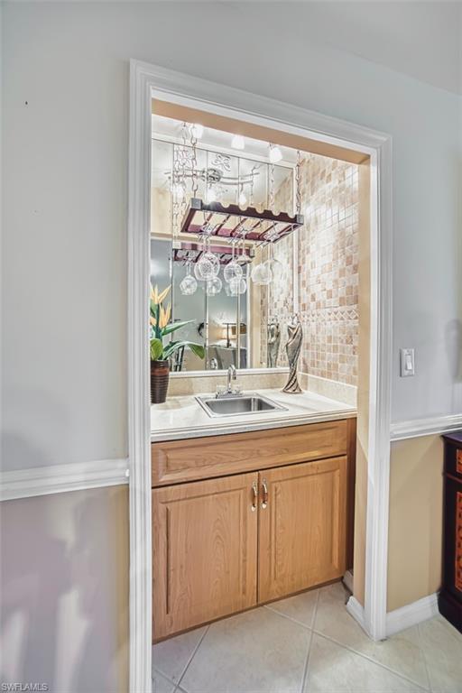 Bar featuring light countertops, brown cabinetry, light tile patterned flooring, and decorative backsplash