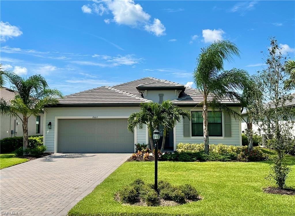 View of front facade featuring a garage and a front lawn