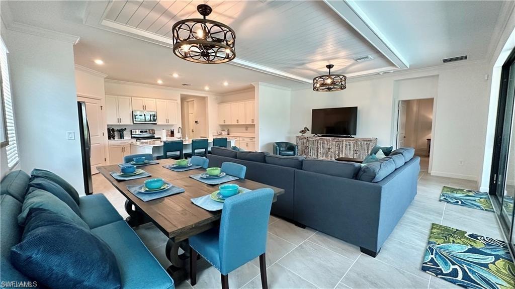 Tiled dining area with a notable chandelier, crown molding, and a raised ceiling