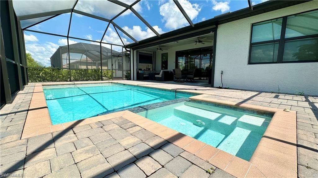 View of swimming pool featuring ceiling fan, an in ground hot tub, a lanai, and a patio area