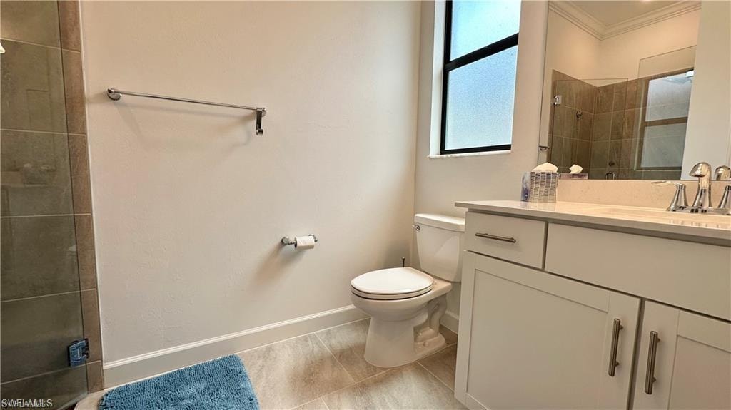 Bathroom with tile flooring, toilet, crown molding, and large vanity