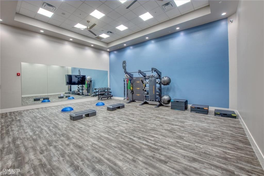 Workout room with a towering ceiling, a tray ceiling, hardwood / wood-style floors, and a drop ceiling