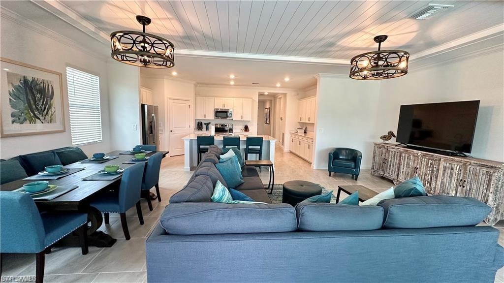Living room featuring ornamental molding, light tile flooring, and a chandelier