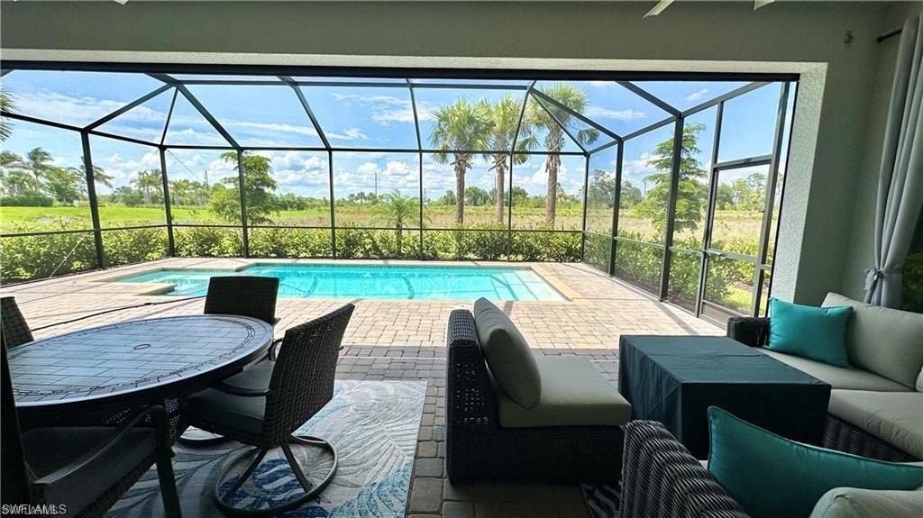 View of swimming pool with glass enclosure and a patio area