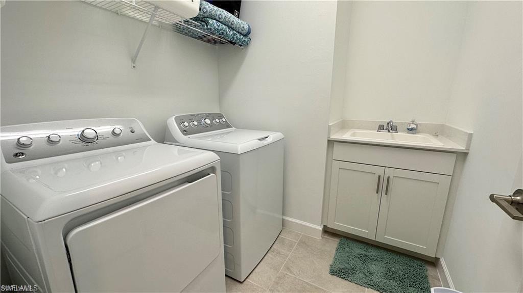 Laundry room featuring sink, independent washer and dryer, light tile floors, and cabinets