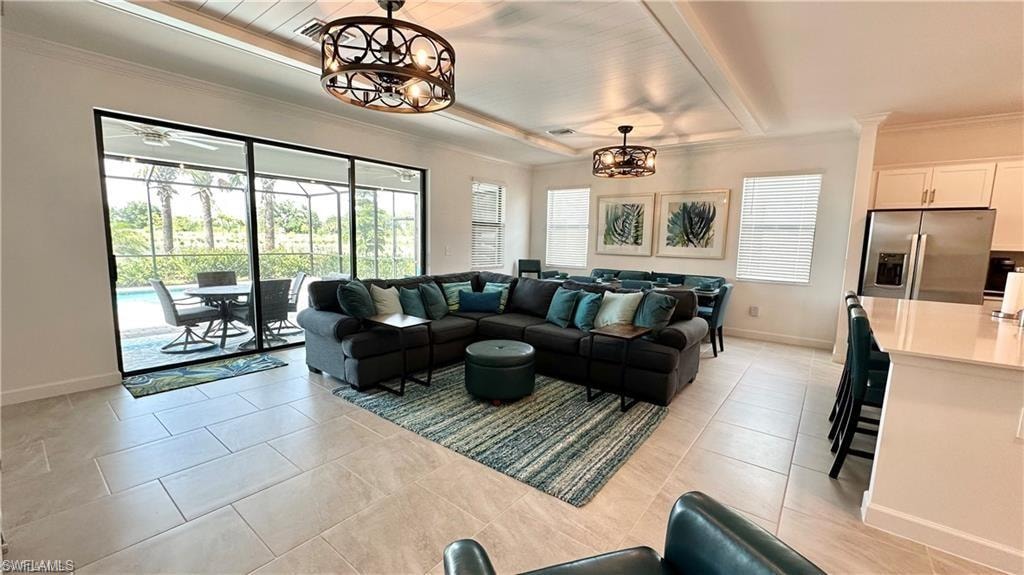 Tiled living room featuring a notable chandelier, a tray ceiling, and crown molding