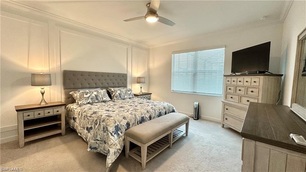 Carpeted bedroom with ornamental molding and ceiling fan