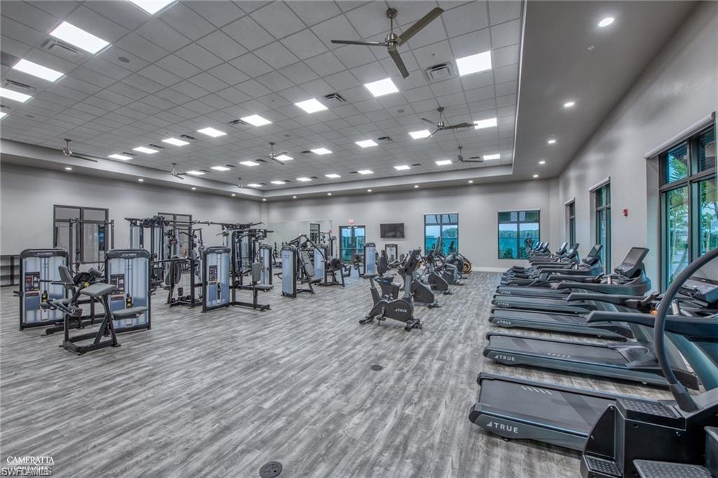Gym featuring a high ceiling, ceiling fan, and a drop ceiling