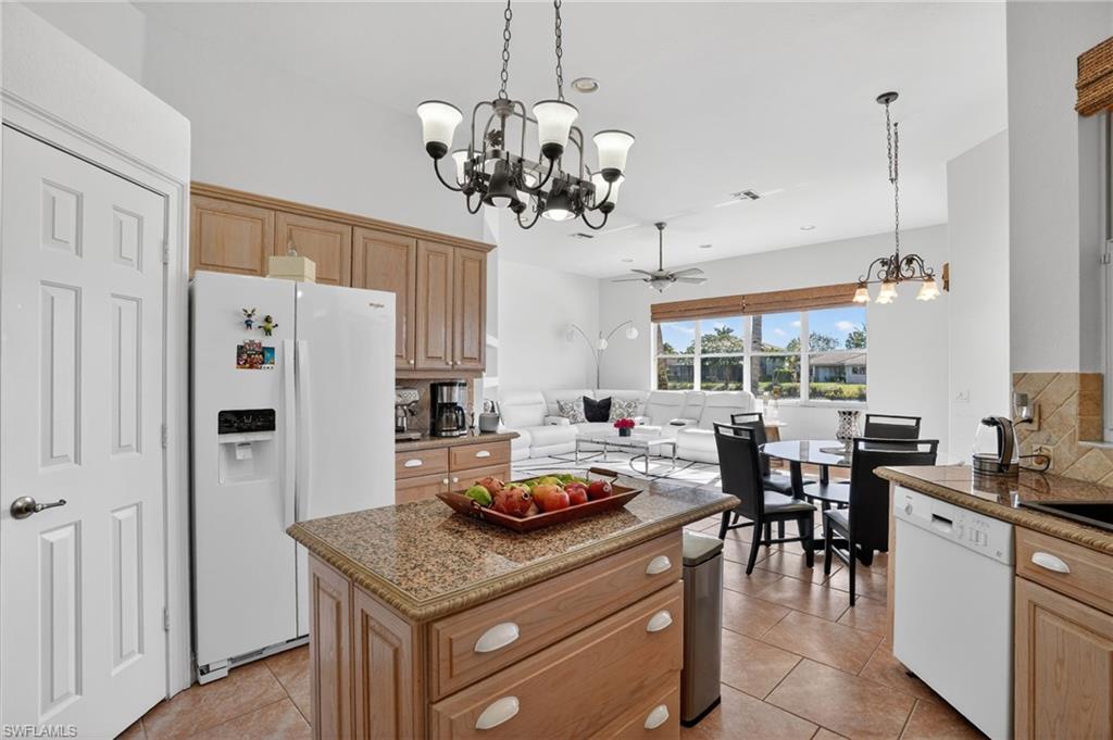 Kitchen with a chandelier, a center island, decorative light fixtures, and white appliances