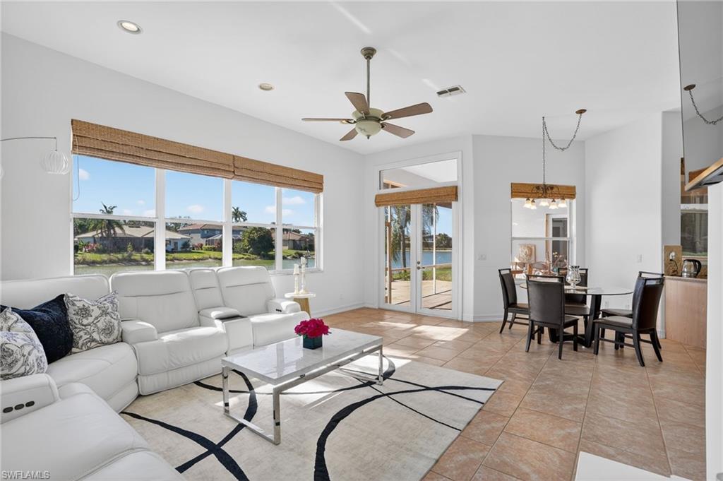 Living room with a water view, light tile patterned floors, ceiling fan, and a chandelier