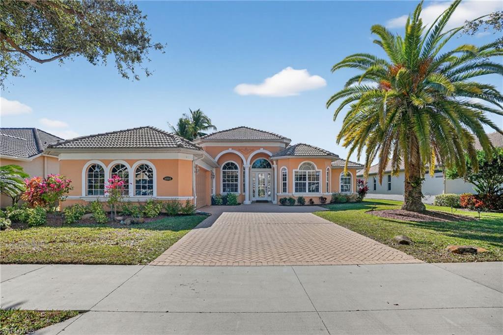 View of front of property featuring decorative driveway, stucco siding, a front yard, a garage, and a tiled roof