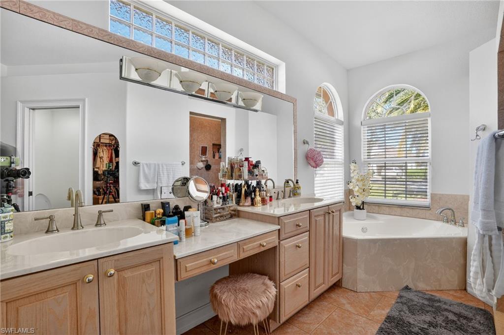 Full bathroom featuring a garden tub, double vanity, healthy amount of natural light, and light tile patterned flooring