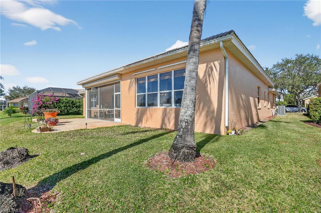 View of property exterior with stucco siding, a patio, and a lawn