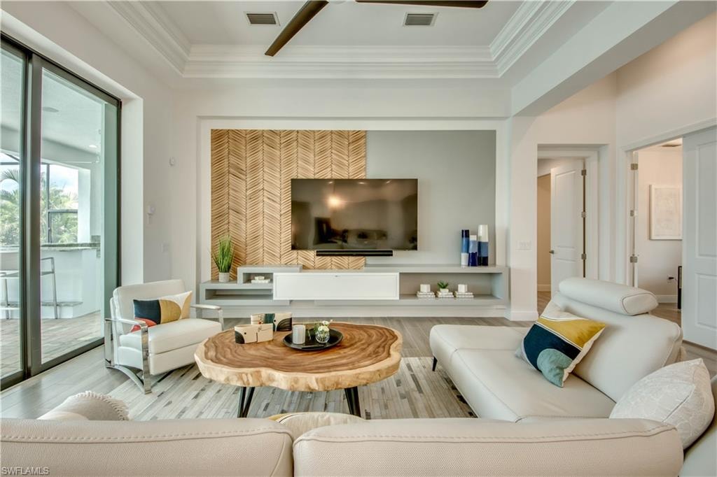 Living area with a chandelier, crown molding, wood tiled floors, stairway, and ceiling fan