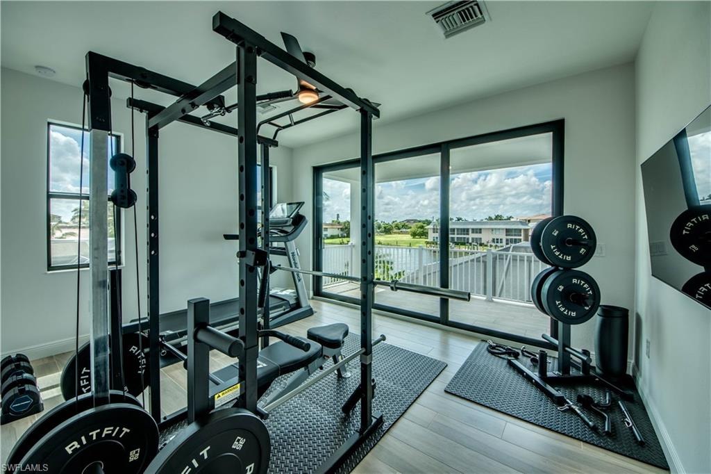 Exercise area featuring wood tiled floors, ceiling fan, and recessed lighting
