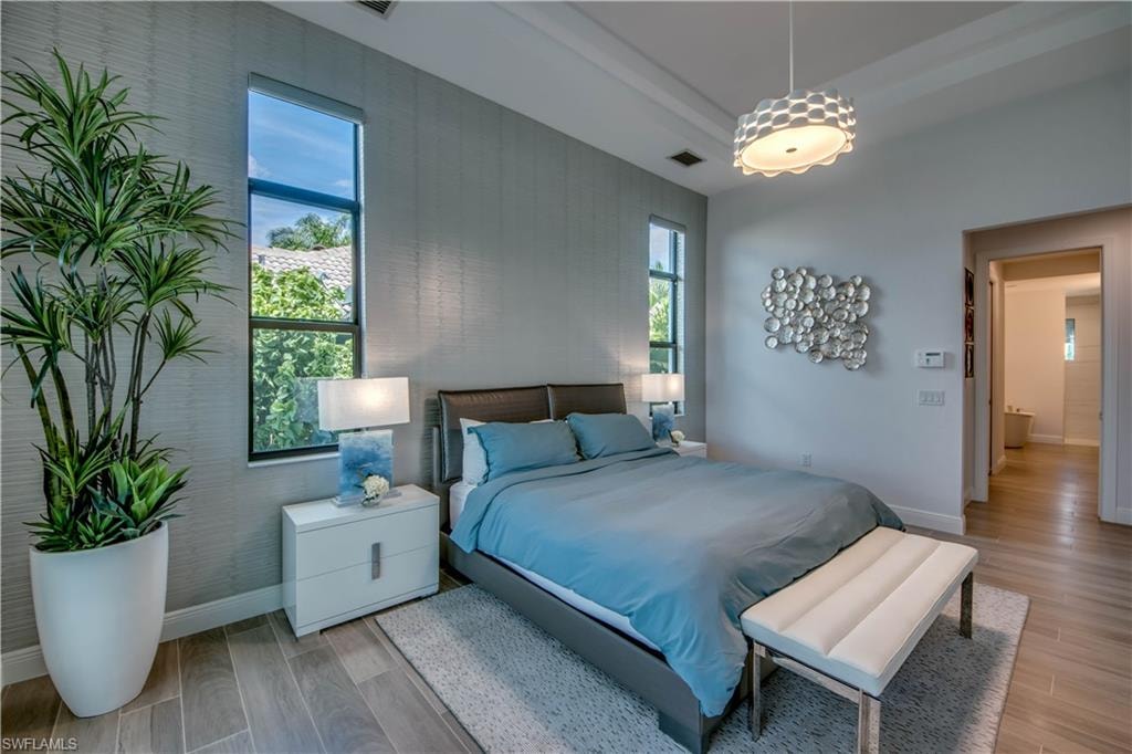 Bedroom with a tray ceiling and wood finish floors