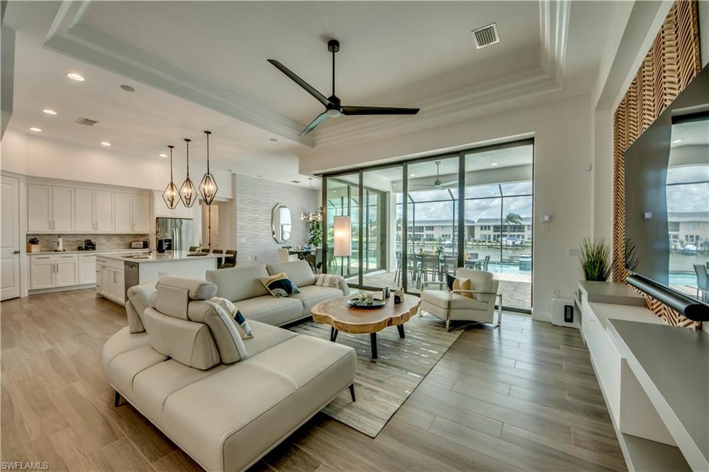 Living area with wood tiled floors, plenty of natural light, ornamental molding, and ceiling fan