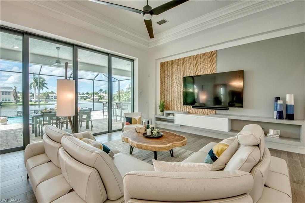 Living area featuring ornamental molding, wood finished floors, and a tray ceiling