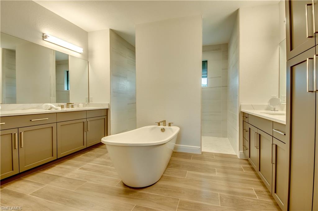 Bathroom with a soaking tub, two vanities, plenty of natural light, and walk in shower