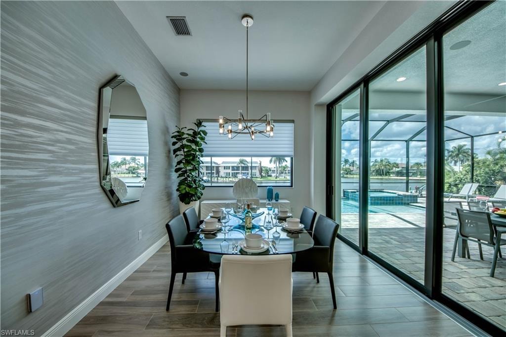 Dining area with a chandelier, wood tiled floors, ornamental molding, a ceiling fan, and a raised ceiling